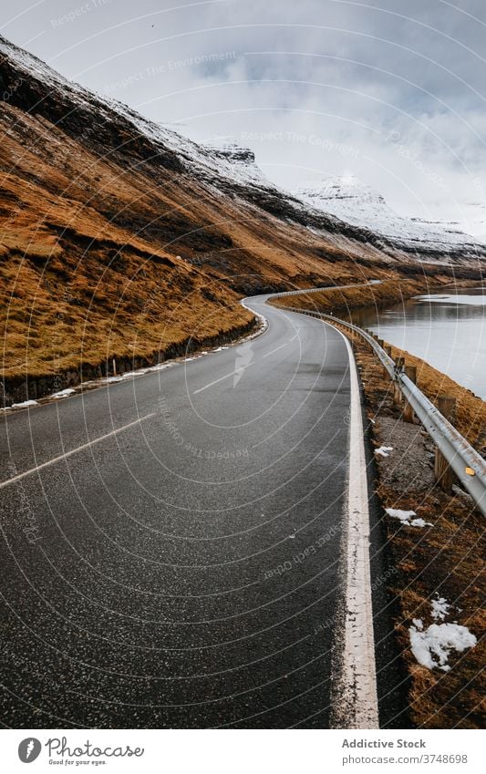Wet mountain road on Faroe Islands winter wet winding spectacular roadway slope river cold faroe islands landscape rock picturesque water weather dry grass