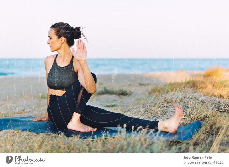 young woman doing yoga exercise on the ground outdoors by the sea people healthy lifestyle balance exercising lifestyles one person sunlight horizontal vitality