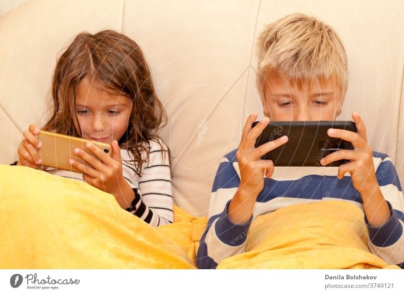 Little girl and boy playing game or watching something on mobile smart phone cartoons mobile phone resting watching cartoons surfing the net connection