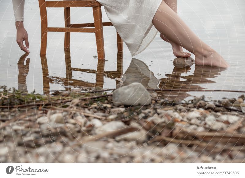 Woman in white dress sitting on a wooden chair in the water Chair Water Lake stones Calm Summer Reflection Relaxation bank Lakeside by hand foot Legs Dress Wait