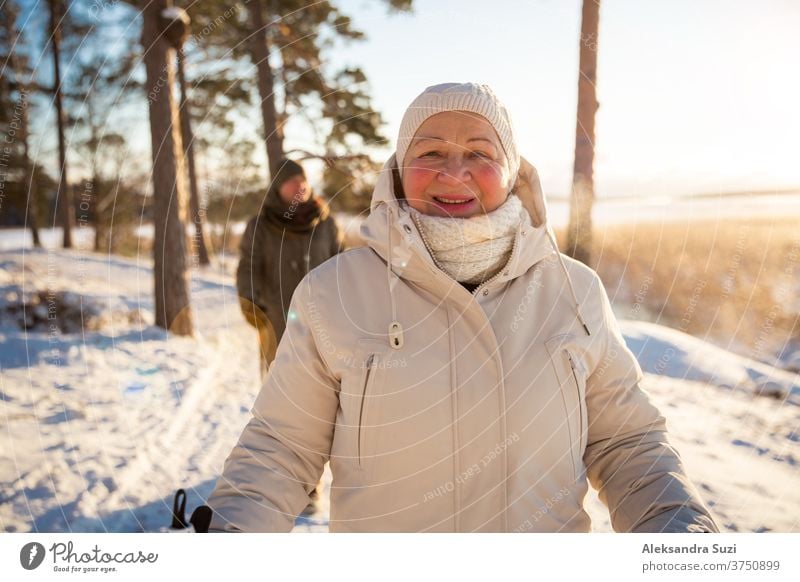 Winter sport in Finland - nordic walking. Senior woman and man hiking in cold forest. Active people outdoors. Scenic peaceful Finnish landscape. senior winter