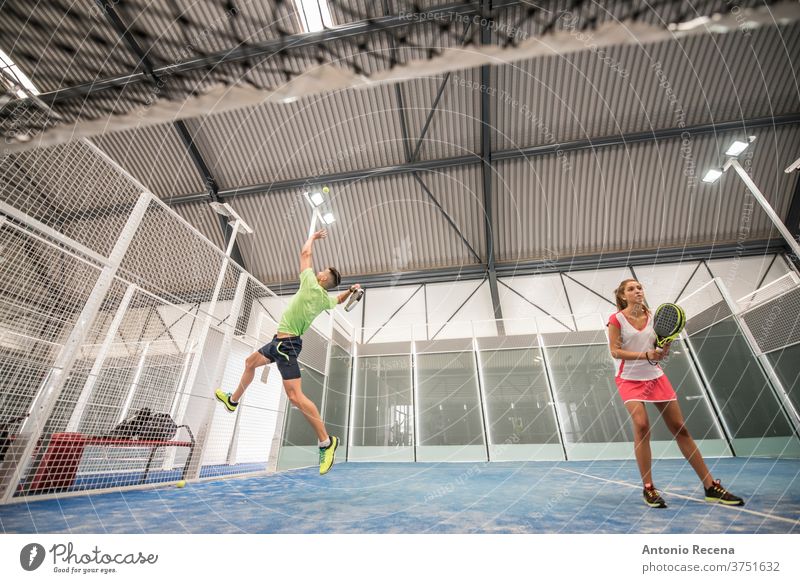paddle tennis indoors training. Wide angle view under the net padel pádel sport sports recreation class court man woman women blue lifestyles shot couple ball