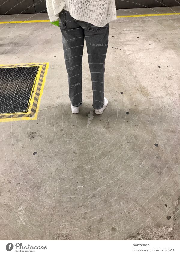 Lower body of a young, fashionably casually dressed woman standing and waiting at a railway station. Markings Platform railway track Wait Lateness Woman