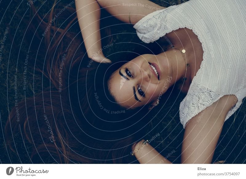 Young dark-haired woman lies on the floor with her hands in her hair and looks radiantly upwards into the camera Young woman Dark-haired brown-haired