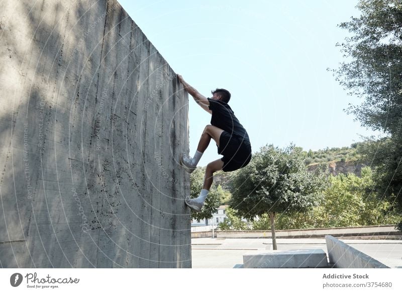 Strong man jumping on wall of building parkour stunt freestyle trick urban city extreme danger male street courage young active handsome activity professional