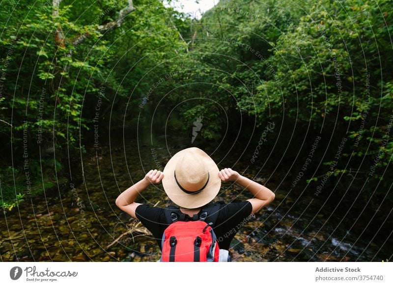 Traveling woman with backpack near pond in woods carefree traveler freedom enjoy forest lake vacation summer female tourist hat calm trip journey wanderlust