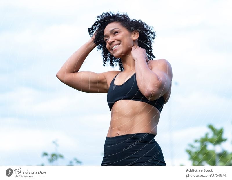 Smiling black sportswoman warming up in park muscular warm up training athlete strong stretch sportswear female ethnic african american workout healthy fit