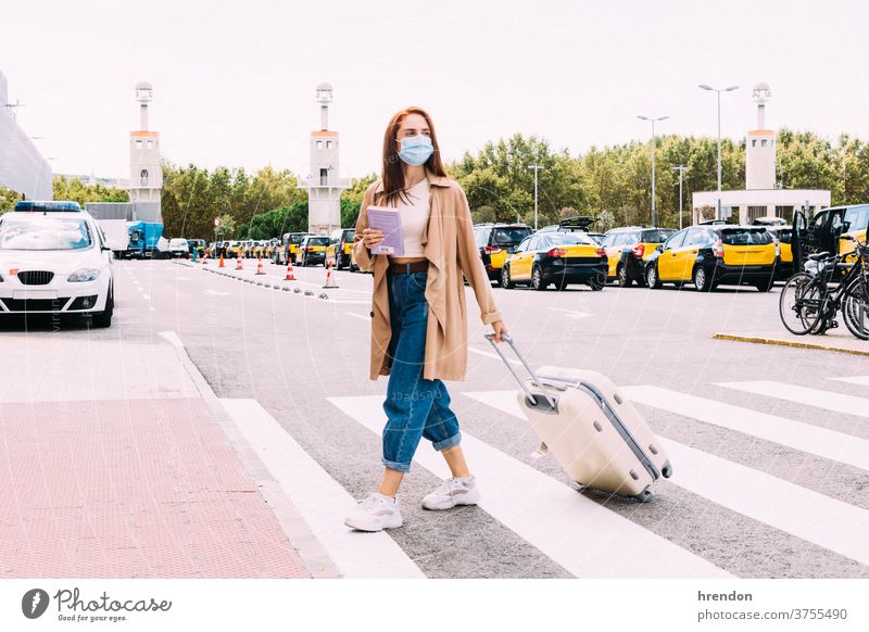 young woman with a face mask crosses the street to take a cab out of the train station coronavirus tourism transportation tourist public journey trip commuter