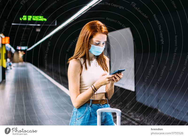 young woman with face mask checks her smartphone while waiting for the subway transportation public journey tourist trip commuter train traveling voyage economy