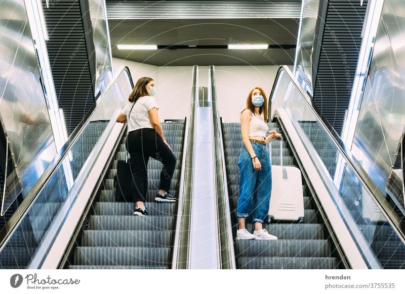 two young tourists wearing face masks use the subway escalators stairway terminal coronavirus tourism transportation public journey trip commute train staircase