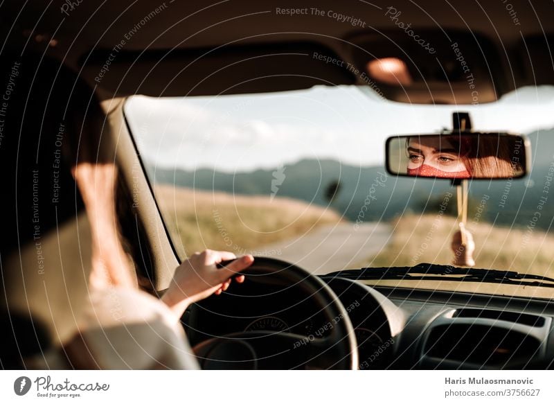 Woman with mask driving a car, face in review mirror , traveling in covid-19 time adventure auto automobile coronavirus drive driver face mask hand in the car