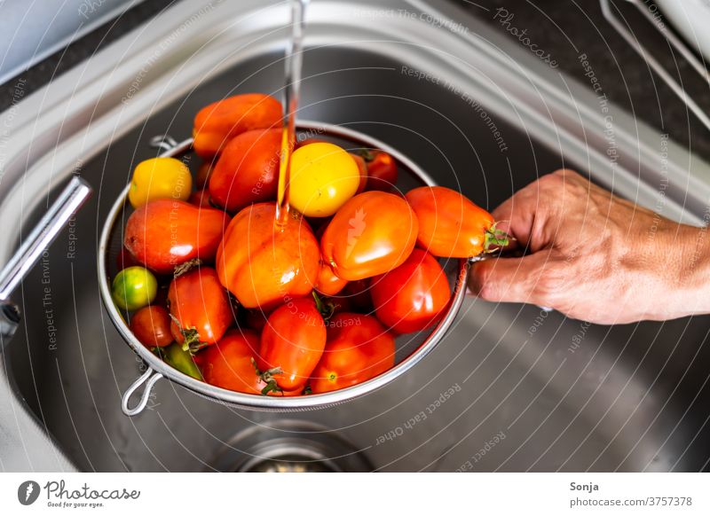Man washes fresh raw tomatoes in a kitchen sieve over a sink Wash Kitchen sink Sieve by hand stop subsection Tap Water Cleaning cake Interior shot Nutrition