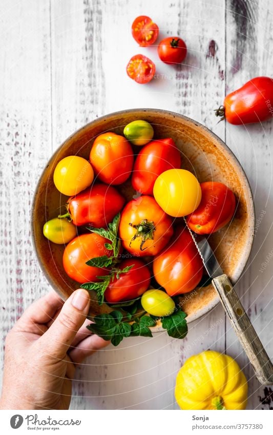 Hand with a plate of raw tomatoes on a wooden table. Top view, healthy diet. Red Raw Plate Wooden table by hand stop Knives Vegetable Colour photo Nutrition