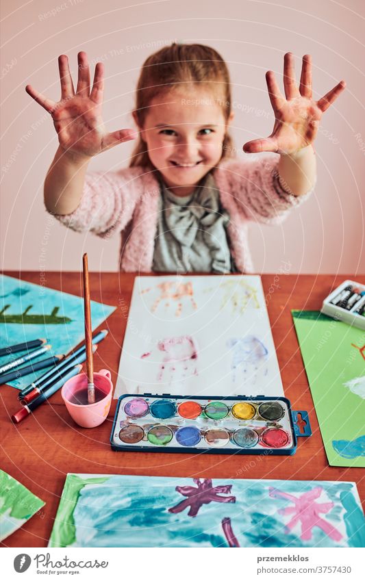 Little girl preschooler showing painted colourful hands child painting dye education colorful art home paper childhood creation craft table creativity kid