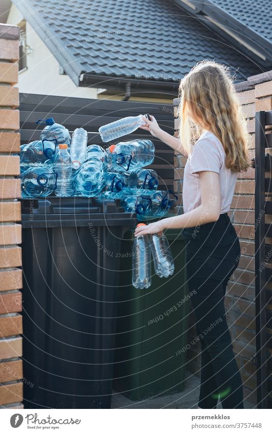 Young woman throwing out empty used plastic water bottles into trash bin blue collect collecting container crushed disposal ecology environment female garbage