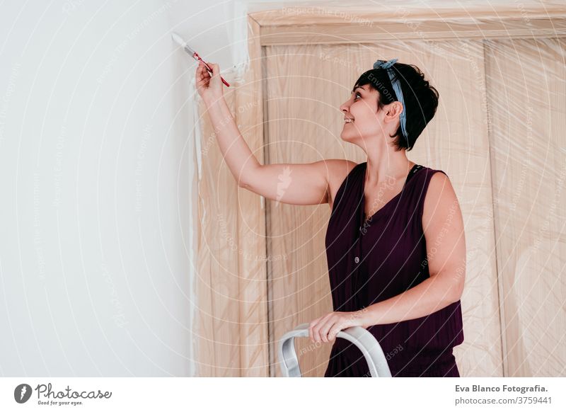happy caucasian woman painting the room walls with white color. Do it yourself and new home concept house brush young new house painter bricolage america solo