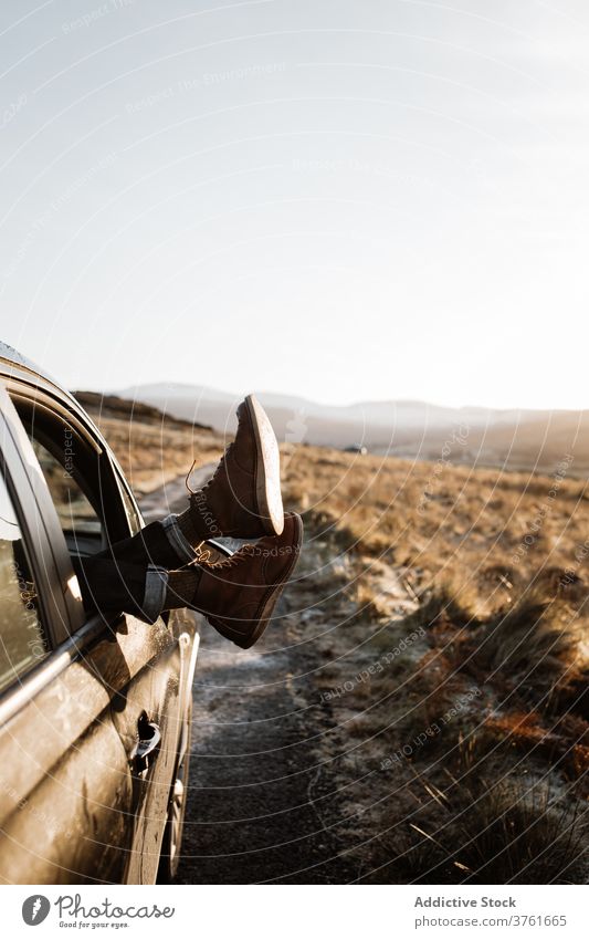 Crop traveler relaxing in car in mountains leg window sunrise highland journey road trip scottish highlands scotland uk united kingdom lying tourist vacation