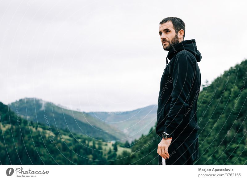 Young male nature explorer enjoying the view on op of the mountain adult adventure alone bearded casual caucasian cloudy countryside dawn environment freedom