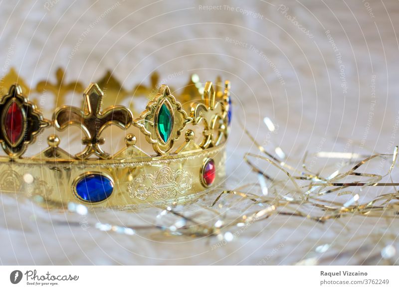 Royal gold crown, with colored gems and diamonds, on a white background with golden bands surrounding it. christmas decoration holiday jewelry royalty king