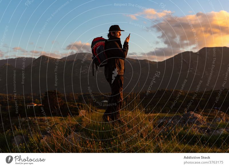 Male traveler talking on smartphone in mountains hiker speak man sunset admire using highland male rock cellphone device sit trekking journey adventure trip guy