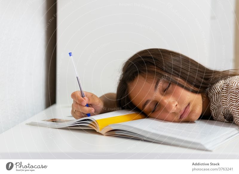Tired student sleeping at table tired woman exhausted prepare exam textbook overwork female education study young knowledge asleep fatigue homework research