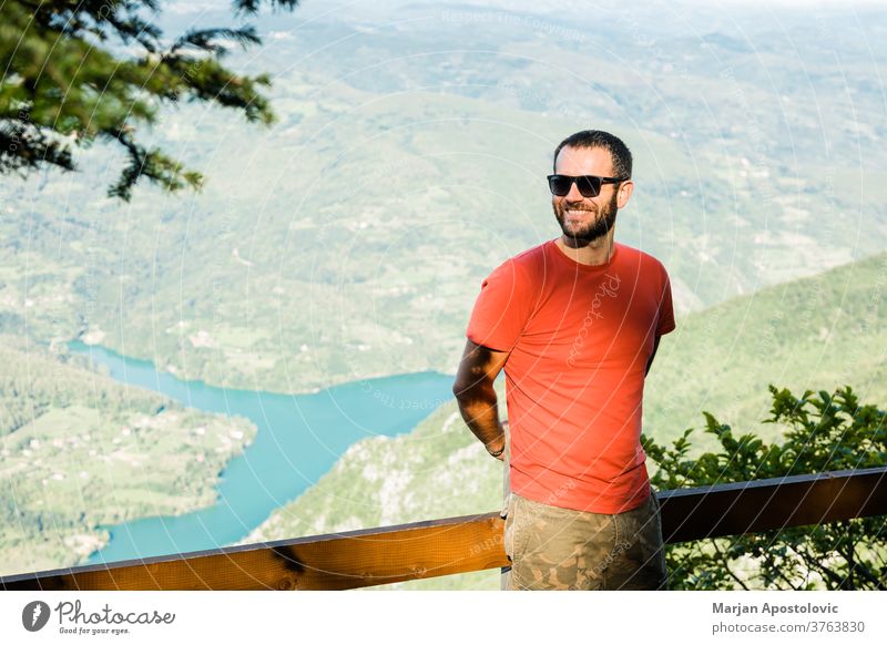 Young man in the mountain enjoying the view of the lake adventure alone background beautiful canyon caucasian day edge explore explorer free freedom guy