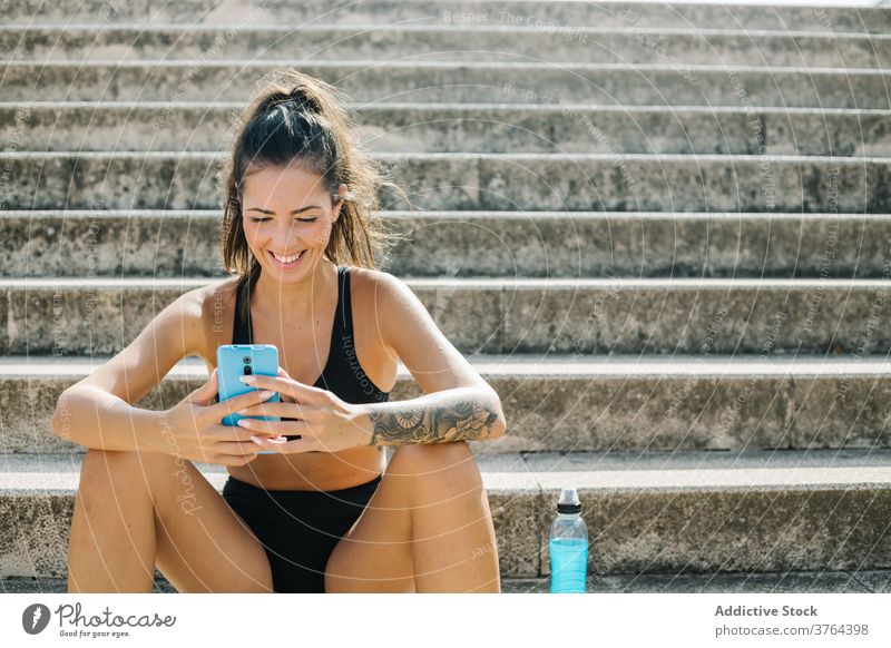 Sportswoman using mobile phone on stairway sportswoman smartphone rest training workout gadget athlete device relax urban cellphone step break online connection