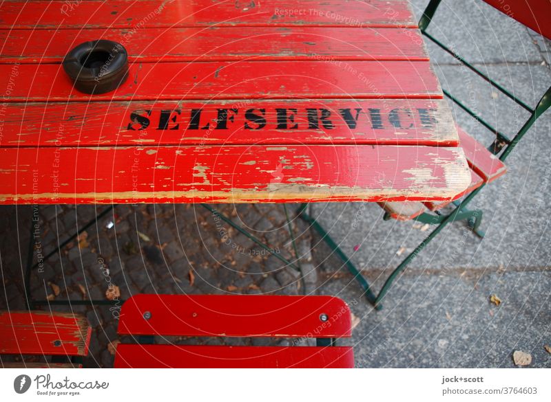 Self-service labelled on wooden table Table Folding chair English Typography Stencil letters Word Ravages of time Capital letter Second-hand Ashtray Clue