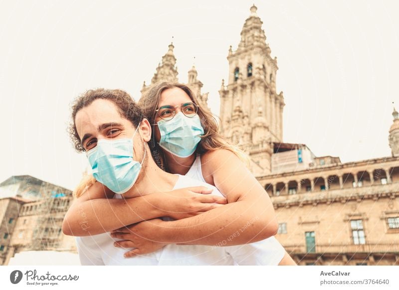 Young couple having a good time while traveling having the masks put on adult touching pandemic multicultural responsibility woman female young emotion exterior