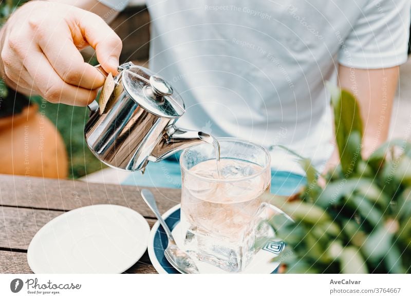 Young male serving an ice tea in a modern bar dry close herb man heat isolated health asia drink teacup breakfast hand pouring china white old hot beverage