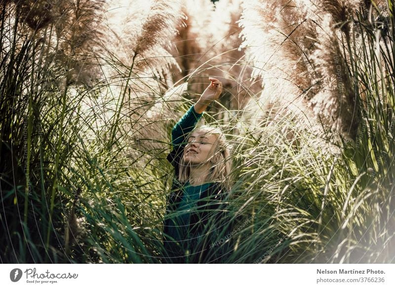 Portrait of a caucasian blonde woman around tall and beautiful plants with the sun in the background. sunny natural light portrait young Portrait photograph