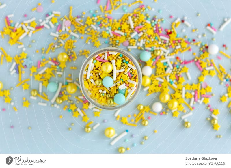 Yellow sugar sprinkles grainy on blue background, close-up flat lay colorful candy sweet food dessert birthday holiday pink cake confetti closeup yellow party