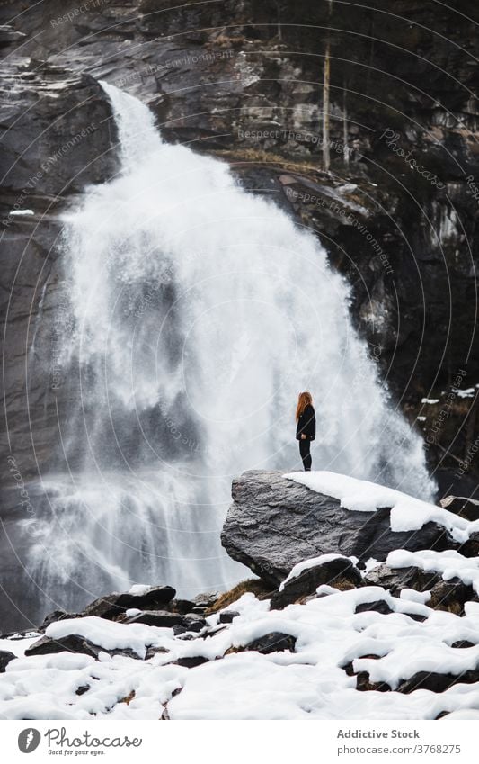 Female hiker near waterfall in winter woman travel observe admire stream power female germany austria amazing rock mountain vacation explore traveler nature