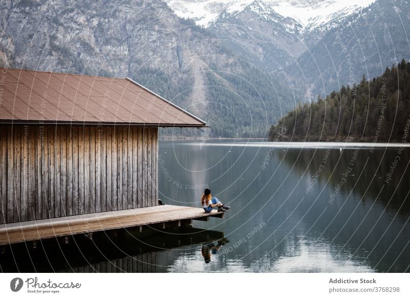 Woman on wooden pier near lake mountain traveler woman wanderlust relax solitude highland reflection pond female germany austria quay scenery calm tranquil snow