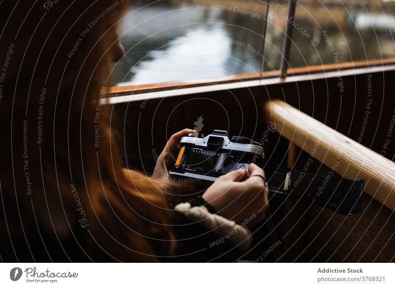Woman changing film in retro photo camera while travelling in boat woman trip photographer vessel old fashioned autumn change shot female traveler lake journey