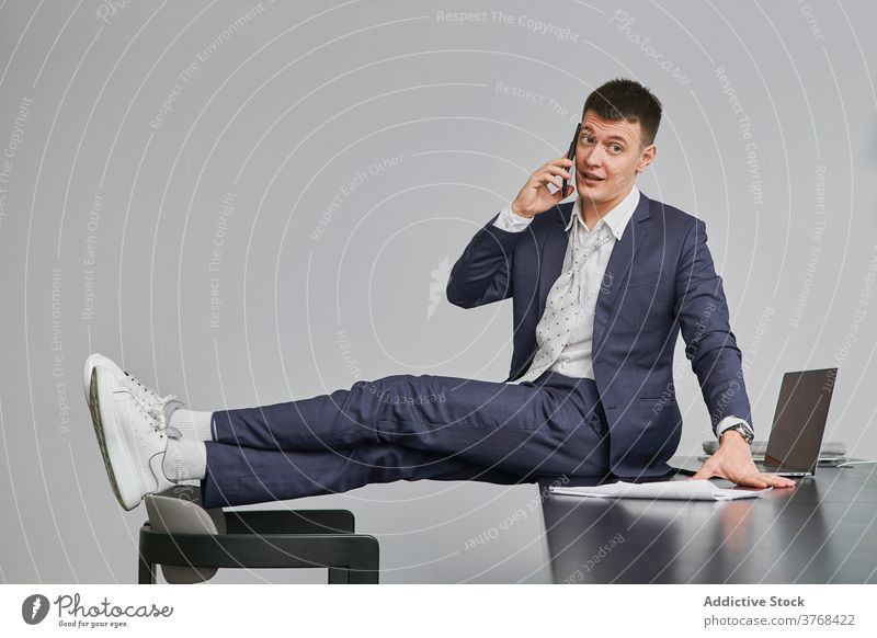 Stylish businessman speaking on cellphone in office project smartphone discuss sit table entrepreneur style male workplace chair conversation occupation device
