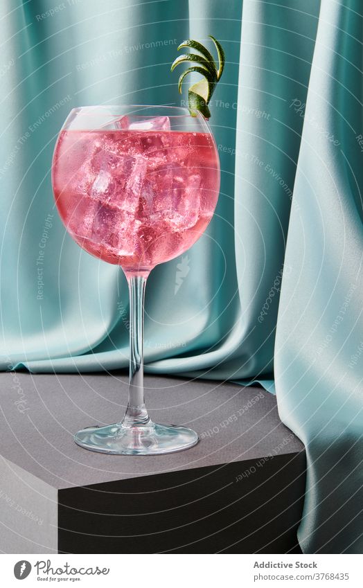 Glass of Cosmopolitan refreshing cocktail on table cosmopolitan lime alcohol glass refreshment beverage drink peel ice cube crystal goblet red bar cool liquid