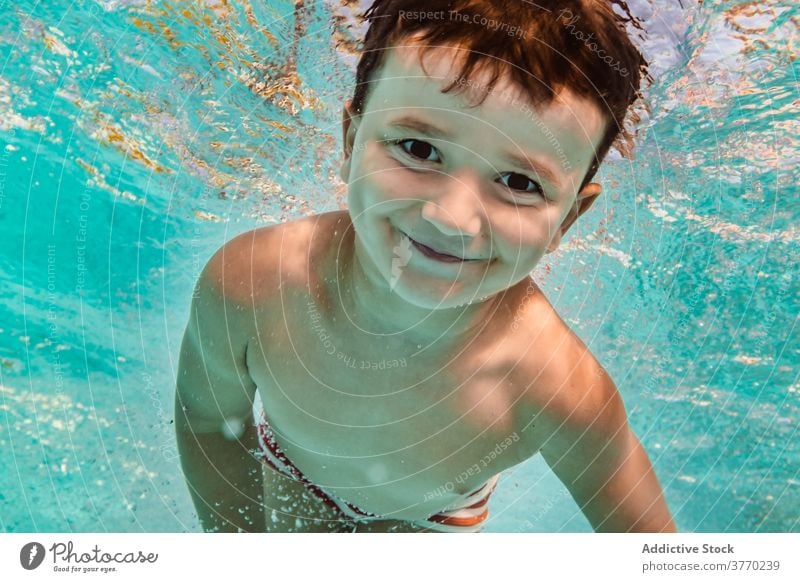 Cheerful boy in swimming pool kid dive playful delight childhood vacation summer having fun water recreation joy aqua cheerful swimsuit clear holiday pleasure