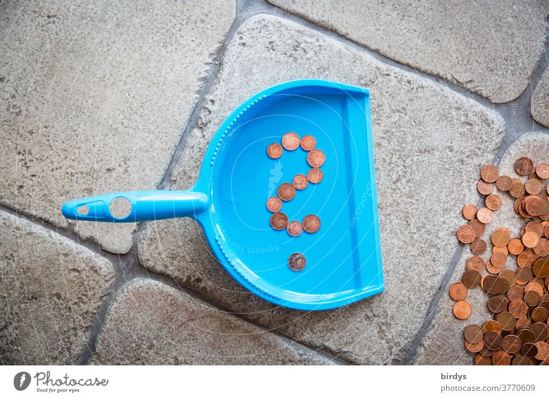 A question mark of red cent coins on a dustpan next to a pile of change, 1 cent and 2 cent - coins, copper money, red money. Abolition of small coins