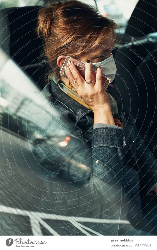 Woman talking on phone using smartphone sitting in a car wearing the face mask to avoid virus infection caucasian covid-19 lifestyle outbreak pandemic woman