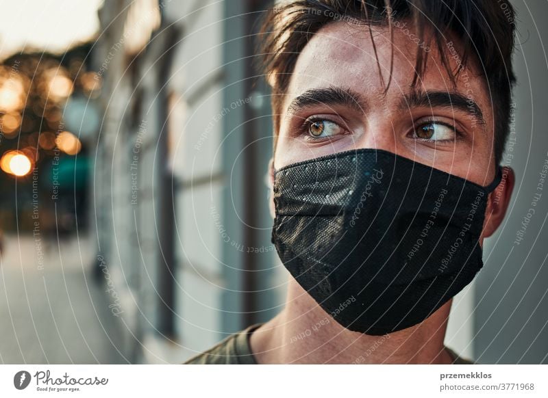 Young man walking along a store front in the city center wearing the face mask to avoid virus infection caucasian conversation covid-19 lifestyle outbreak