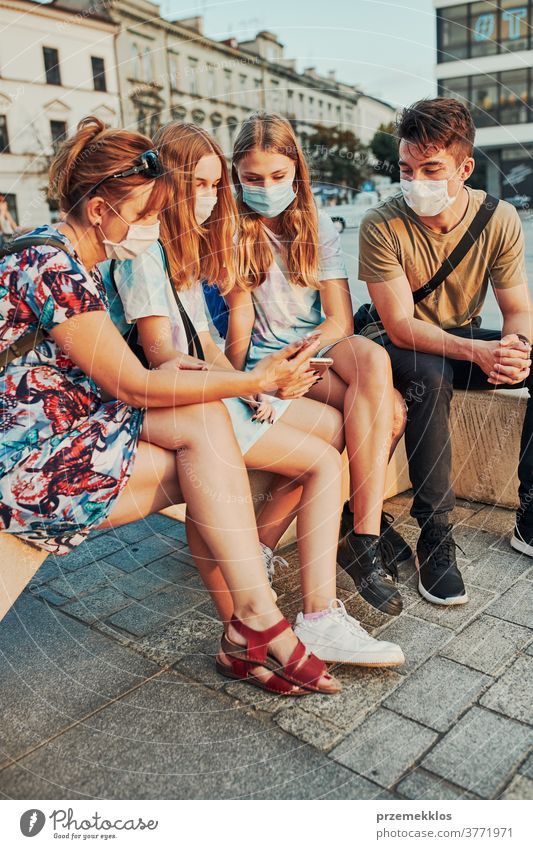 Young women spending time together sitting in the city center wearing the face masks to avoid virus infection caucasian conversation covid-19 female lifestyle