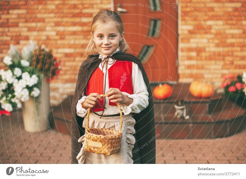 A little girl in a fairy costume with a basket in her hands during the celebration of Halloween goes to visit for treats at home pumpkin celebrate fabulous