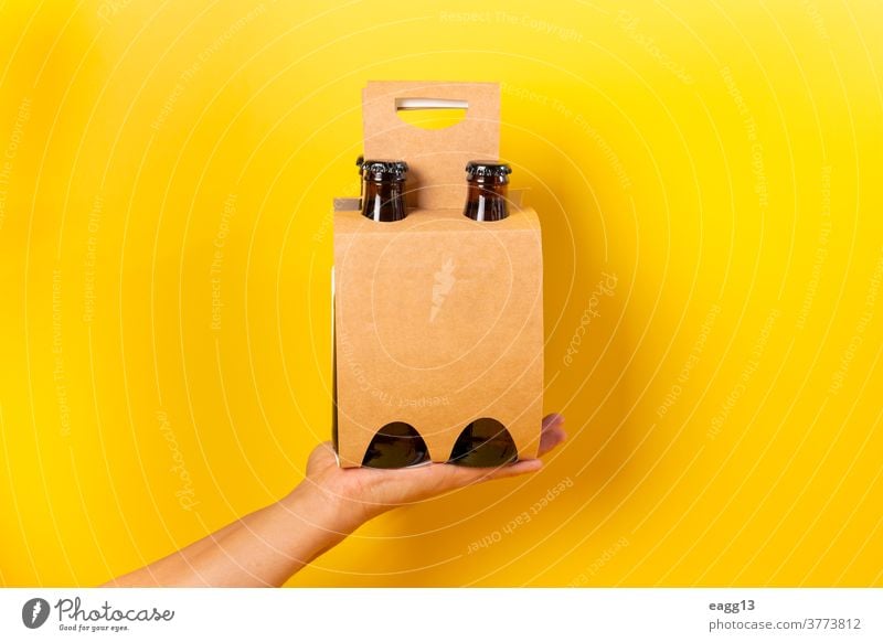 Hand holding a four pack beer presentation with yellow background ale bavarian belgian beverage booze bottle bottles box brand branding brewery carton case