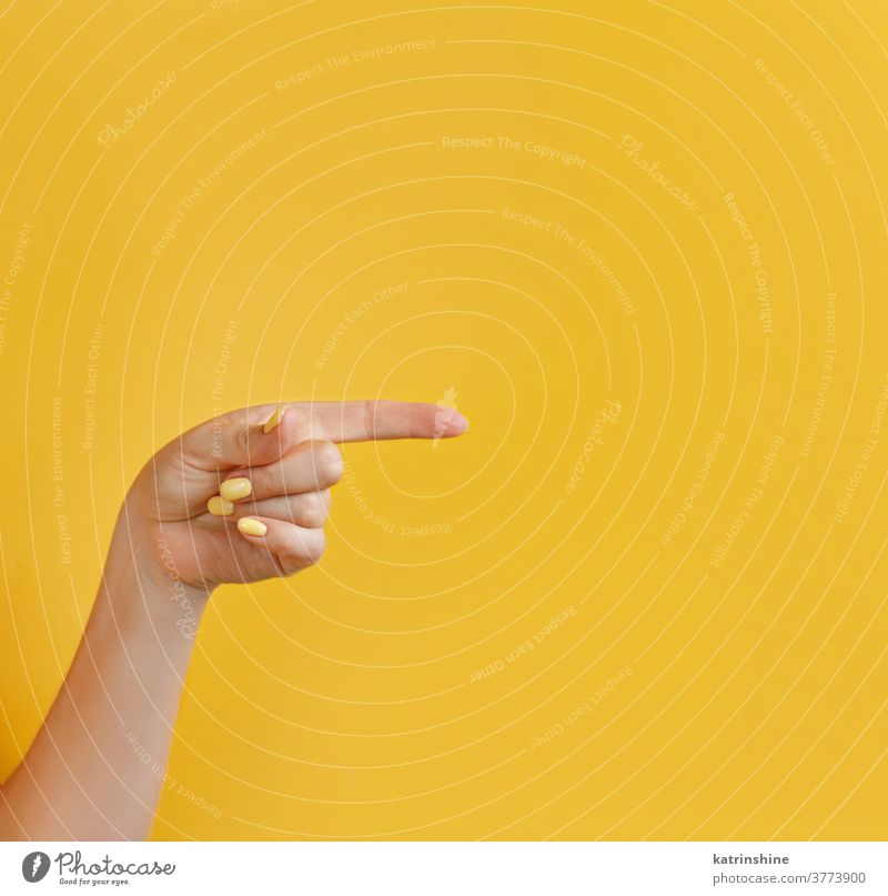 Close up of female hand pointing away on yellow background monochrome bright woman faceless closeup concept copy space negative space Gesture Arm Sign Nonverbal