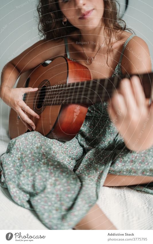 Positive woman playing guitar in bedroom guitarist music cheerful laugh talent entertain carefree instrument female ethnic acoustic cozy home happy musician