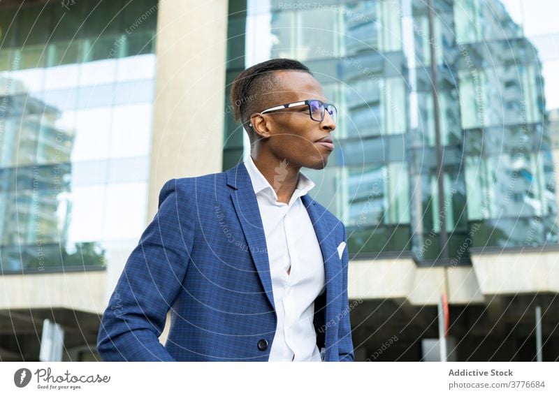 stylish and handsome African businessman American man in blue pants and a  in black T-shirt fashion look holding the bag walking on the street Stock  Photo