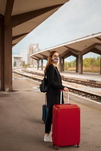 Woman with mask and travel bag waiting on public train station adult attractive baggage beautiful business caucasian city coronavirus covid-19 female journey