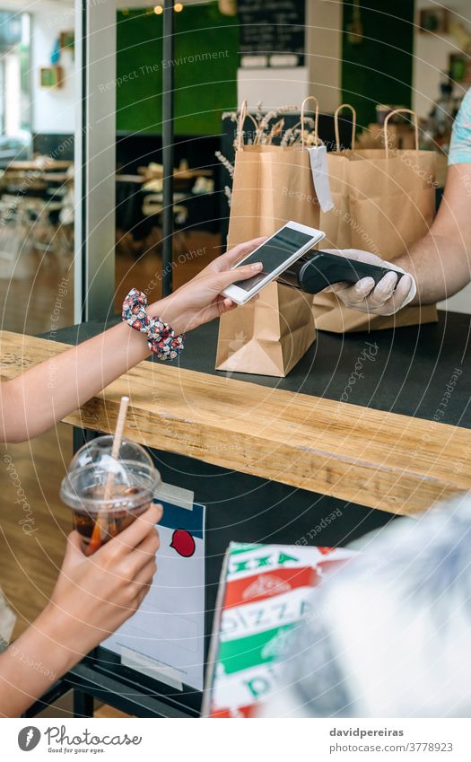 Unrecognizable woman paying with mobile a take away order unrecognizable nfc pos terminal food delivery drink cell phone restaurant picking up outside cafeteria