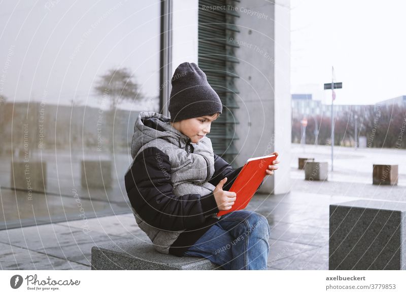 7 year old boy playing online game on tablet computer outdoors in winter child kid technology little people digital young fun internet childhood lifestyle